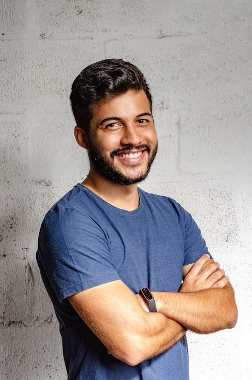 Free Portrait of a happy man with arms crossed, exuding confidence and friendliness. Stock Photo